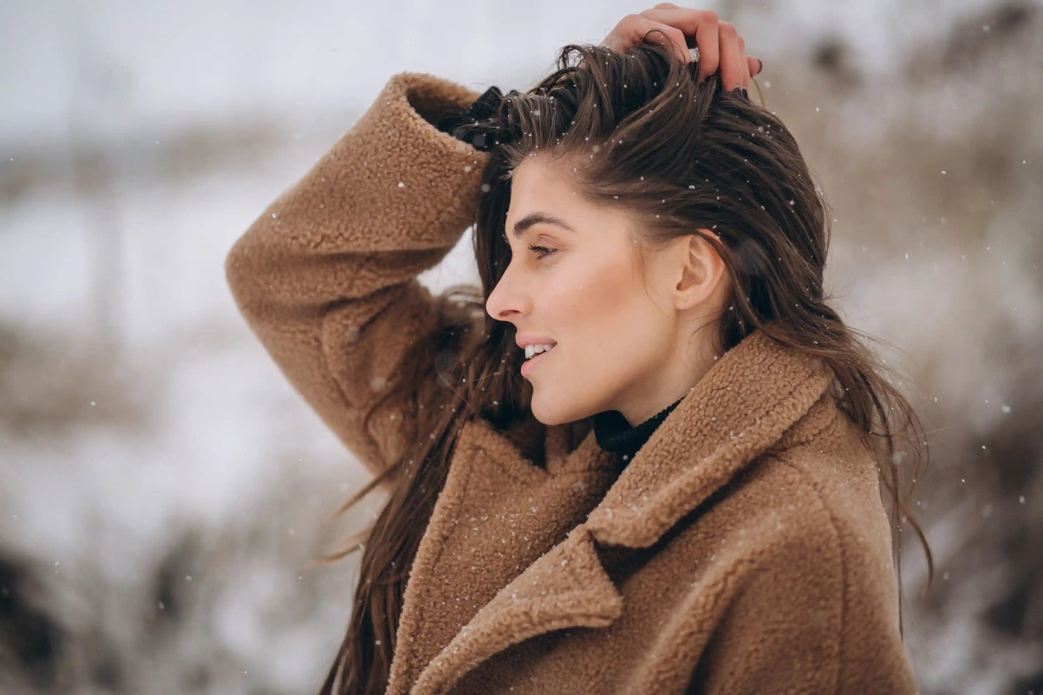 Une femme se touche les cheveux sous la neige